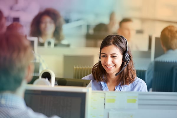 Kvinna på kontor vid dator med headset på