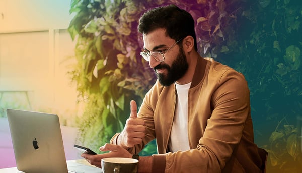 Man vid laptop och mobil i handen