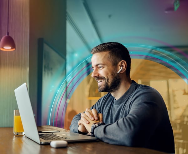 Man på café vid laptop med hörlurar